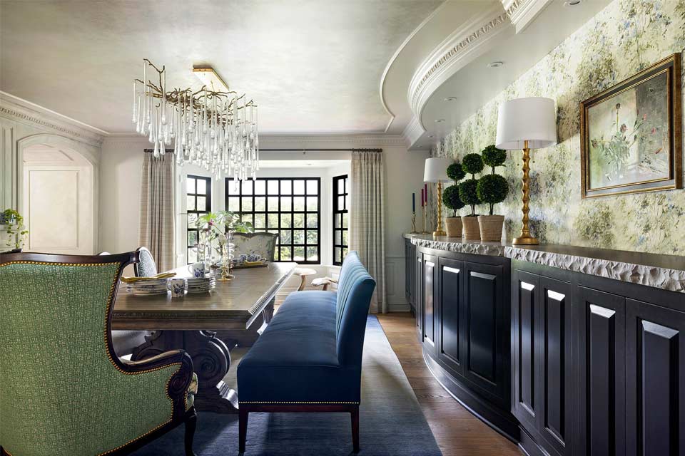 Vinting inspired formal dining room with long wooden dining table, blue velvet bench, chandelier and blue side cabinets.